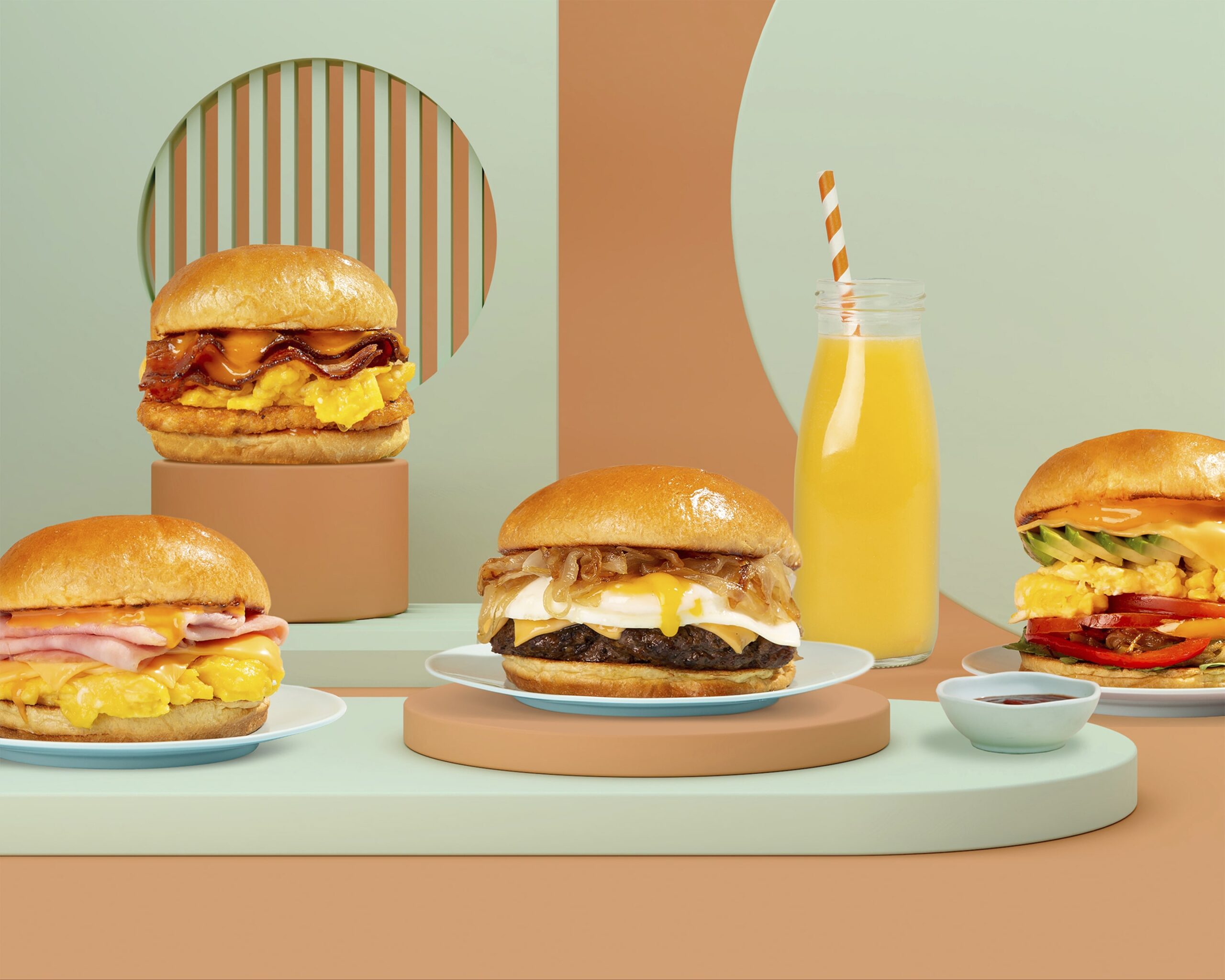 Imagen de cuatro sándwiches de desayuno y un vaso alto de jugo de naranja